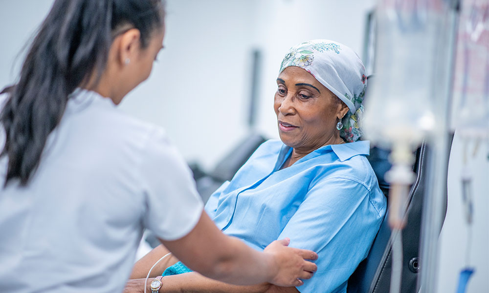 A cancer patient looks on as a female physician or nurse tends to her